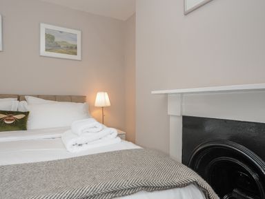 A bedroom with a bed white linens folded towels and a lamp next to a fireplace at Hobbs Cottage in Sticklepath