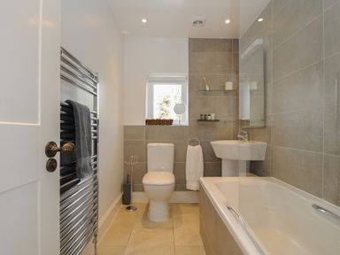 A bathroom with a toilet sink bathtub and towel rack at Hobbs Cottage in Sticklepath