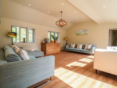 A living room with blue sofas wooden sideboard and wooden floor at Church Farm Barn Dunwich near Westleton