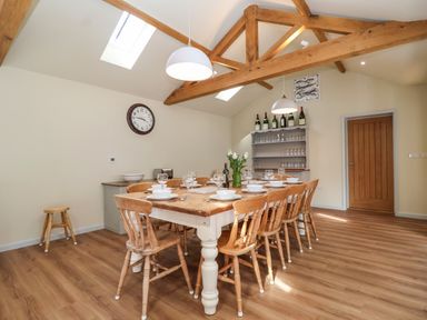 A dining room with a wooden table set for eight people wooden chairs wooden beams on ceiling at Church Farm Barn Dunwich near Westleton