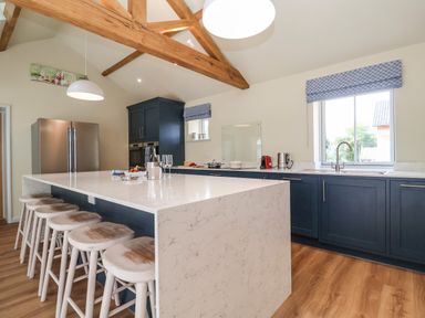 A kitchen with a large marble island and wooden stools at Church Farm Barn in Dunwich near Westleton