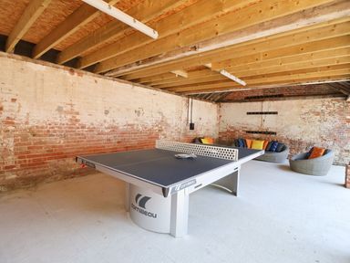 A game room with a ping pong table and round chairs with cushions at Church Farm Barn Dunwich near Westleton