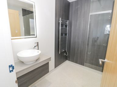A bathroom with a round vessel sink on a countertop a glass shower enclosure and a wall-mounted towel warmer at Classic Lodge 16 in Dyserth