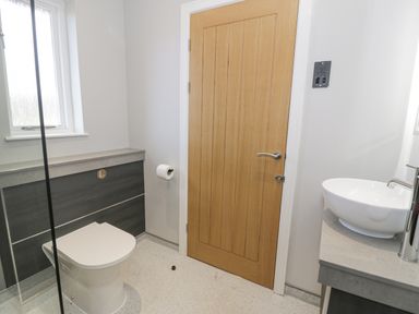 A bathroom with a wooden door a toilet a white sink on a countertop and a window at Classic Lodge 16 in Dyserth