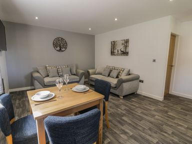 A living room with two sofas a dining table set with plates and glasses at Classic Lodge 16 in Dyserth