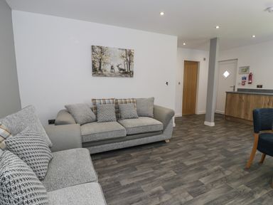 A living room with two sofas a painting on the wall and a wooden floor at Classic Lodge 16 in Dyserth