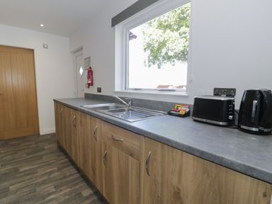 A kitchen counter with a sink toaster kettle and tea bags near a window at Classic Lodge 16 in Dyserth