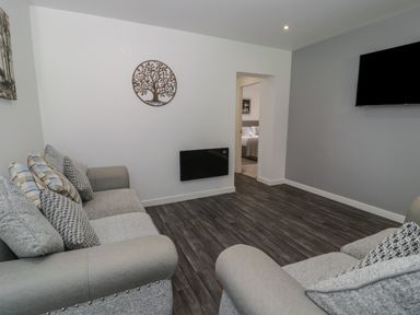 A living room with two sofas with cushions a wall-mounted TV and wall art at Luxury Lodge 69 in Dyserth