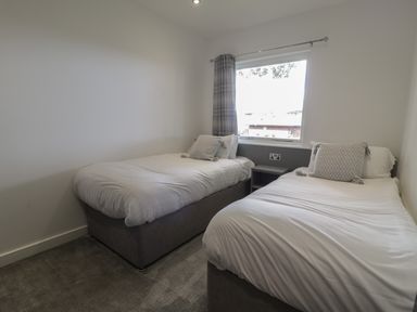 A bedroom with two single beds and a window with curtains at Luxury Lodge 69 in Dyserth