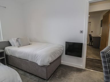 A bedroom with a single bed a pillow a bedside table and a chair at Luxury Lodge 69 in Dyserth