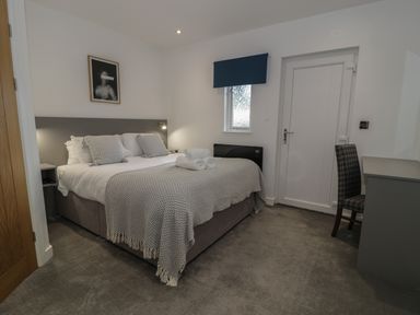A bedroom with a made bed rolled towels a chair and a window at Luxury Lodge 69 in Dyserth