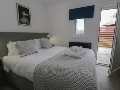 A bedroom with a bed covered with pillows and towels next to a window and an open door at Luxury Lodge 69 in Dyserth