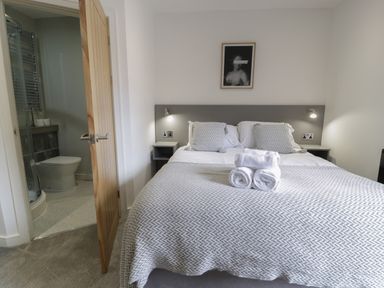 A bedroom with a double bed two pillows and folded towels on the bed next to a partially open door leading to a bathroom at Luxury Lodge 69 in Dyserth