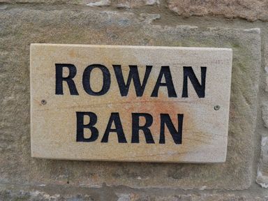 A stone plaque with the text Rowan Barn on a stone wall at Rowan Barn in Bellingham