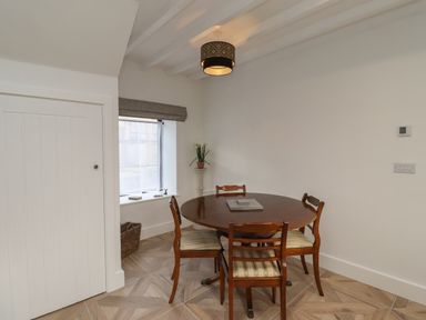 A dining room with a round wooden table and four chairs near a window with a gray blind at Rowan Barn in Bellingham