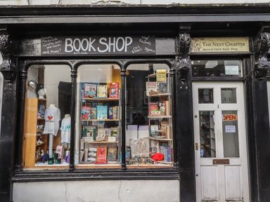 A book shop storefront with books displayed in windows and a white door at The Next Chapter in Bellingham