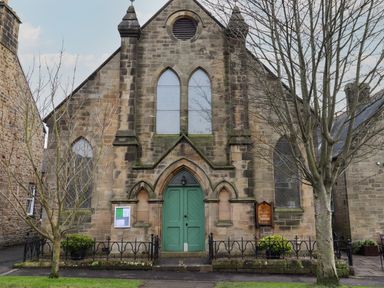 Front view of a stone church with green double doors and stained glass windows surrounded by leafless trees Rowan Barn Bellingham