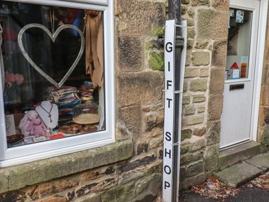 A shop window displaying gifts and a vertical sign reading gift shop outside a stone building at Rowan Barn in Bellingham