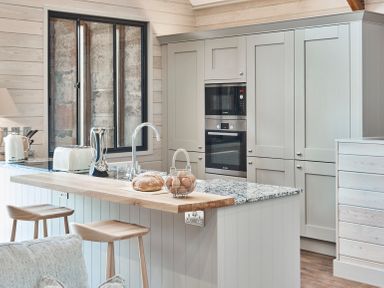 A kitchen with a wooden breakfast bar stools oven microwave and countertop appliances at The Hayloft in Humshaugh