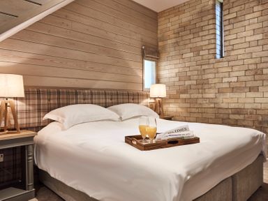 A bedroom with a bed with white linens two bedside tables with lamps and a tray with beverages and newspapers at The Hayloft in Humshaugh