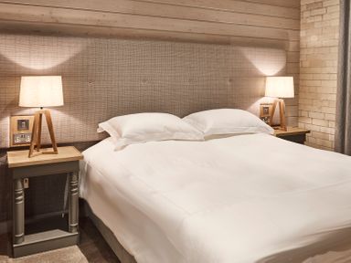 A bedroom with a double bed with white bedding two bedside tables with lamps and wood paneled walls at The Hayloft in Humshaugh