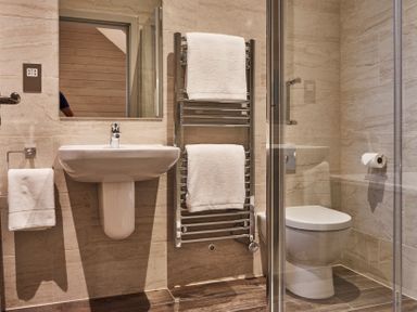 A bathroom with a sink mirror towel rail toilet and glass shower enclosure at The Hayloft in Humshaugh