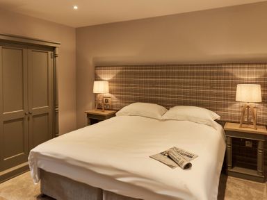 A bedroom with a double bed two bedside tables two lamps and a wardrobe at The Stalls in Humshaugh
