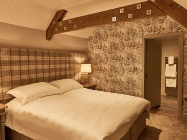A bedroom with a bed a lamp and an open door showing a bathroom at The Stalls in Humshaugh