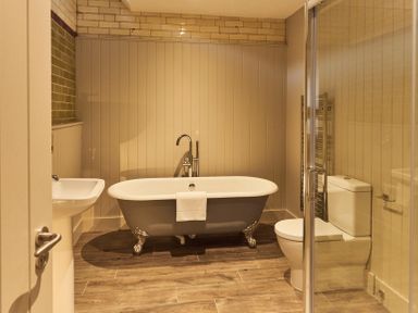 A bathroom with a freestanding bathtub a sink a toilet and a glass shower door at The Stalls in Humshaugh