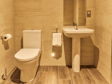 A bathroom with a toilet a sink a mirror and towels at The Stalls in Humshaugh