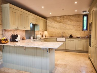 A kitchen with beige cabinets a countertop with a fruit basket coffee machine and a sink at The Carriage House in Humshaugh