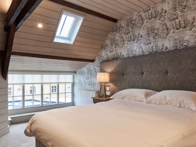 A bedroom with a large bed a bedside table with a lamp and a skylight window at The Carriage House in Humshaugh