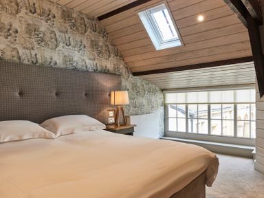 A bedroom with a bed a bedside table with a lamp a skylight and a window at The Carriage House in Humshaugh