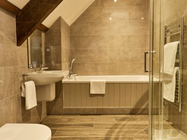 A bathroom with a sink bathtub towels and a glass shower at The Carriage House in Humshaugh