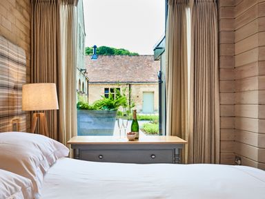 A bedroom with a bed lamp and a wooden table with a bottle and two glasses at The Carriage House in Humshaugh