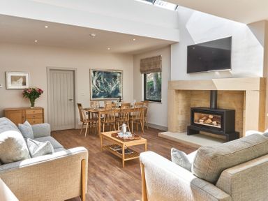 A living room with sofas a dining table a fireplace and a television at The Smithy in Humshaugh
