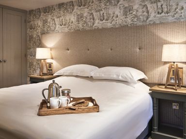 A bedroom with a bed tray holding a coffee pot two cups and a plate on a bed at The Smithy in Humshaugh
