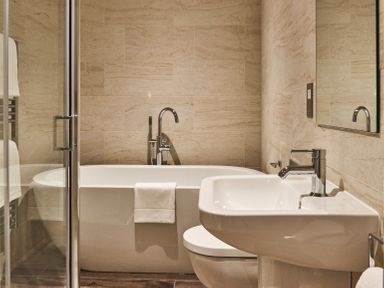 A bathroom with a bathtub sink toilet and a glass shower door at The Smithy in Humshaugh