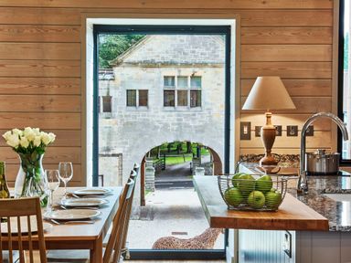 A kitchen with a dining table set with plates and glasses and a countertop with a basket of green apples at The Foal in Humshaugh