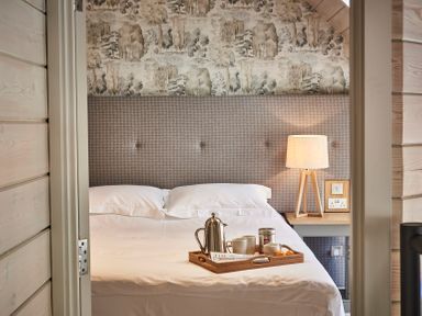 A bed with a tray of coffee mugs and a coffee pot next to a lamp on a bedside table at The Clocktower in Humshaugh