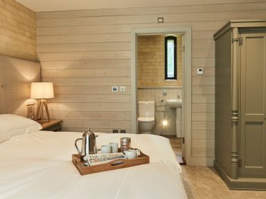 A bedroom with a bed holding a tray with coffee items and a newspaper and an ensuite bathroom at The Clocktower in Humshaugh