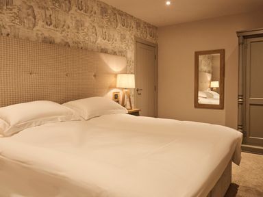 A bedroom with a bed a bedside table lamp a door a mirror and a wardrobe at The Clocktower in Humshaugh