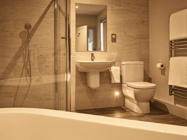 A bathroom with a bathtub shower sink toilet and towel rack at The Clocktower in Humshaugh