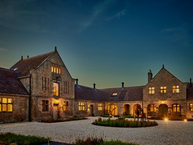 A stone building with lit windows and a courtyard with a sculpture of horses at The Clocktower in Humshaugh