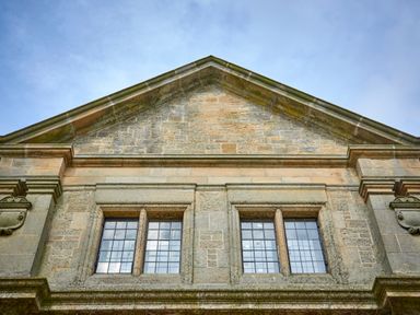 Stone building facade with two rectangular windows under a triangular roof at The Clocktower in Humshaugh