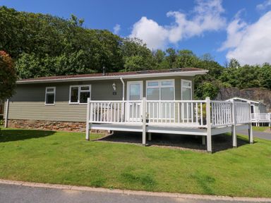 A cabin with a deck and garden at Serenity in Kilgetty