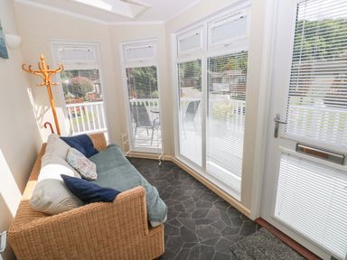 A conservatory with a sofa and coatrack at Serenity in Kilgetty