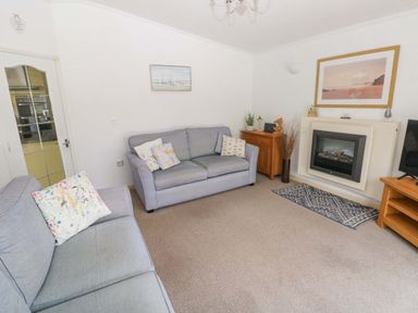 A living room with a sofa and a television at Serenity in Kilgetty