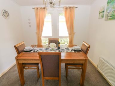 A dining room with a wooden table and chairs at Serenity in Kilgetty