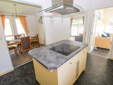 A kitchen with an island and dining area at Serenity in Kilgetty